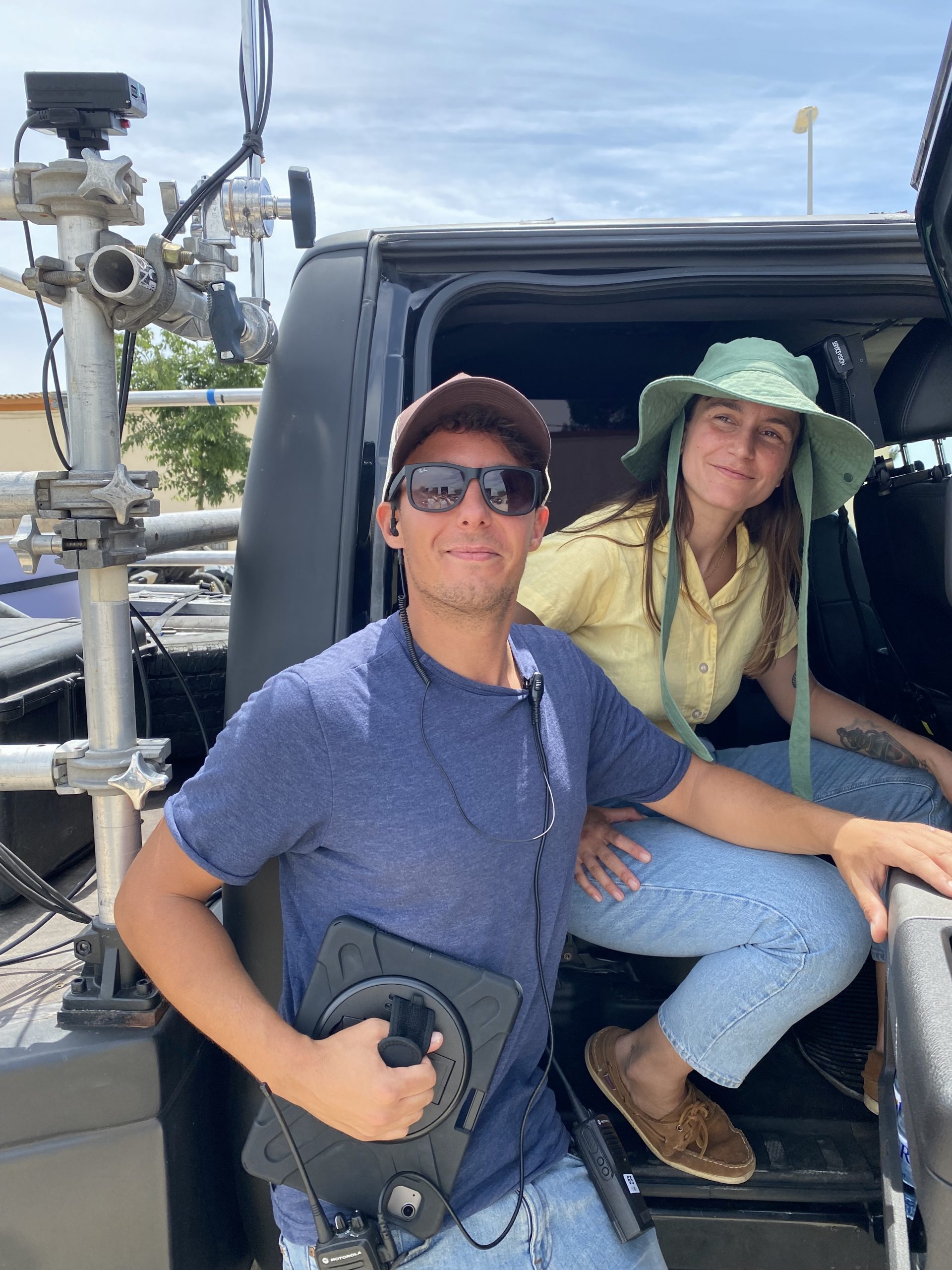 Two Glassy Films crew members in a camera car rig, one holding a remote head controller