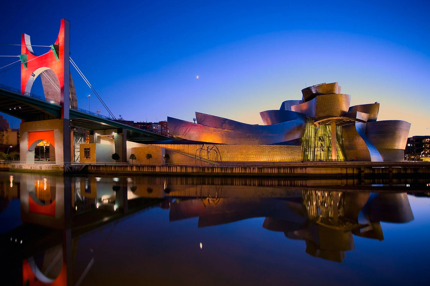 Guggenheim Museum Bilbao and La Salve bridge reflected in the river at dusk