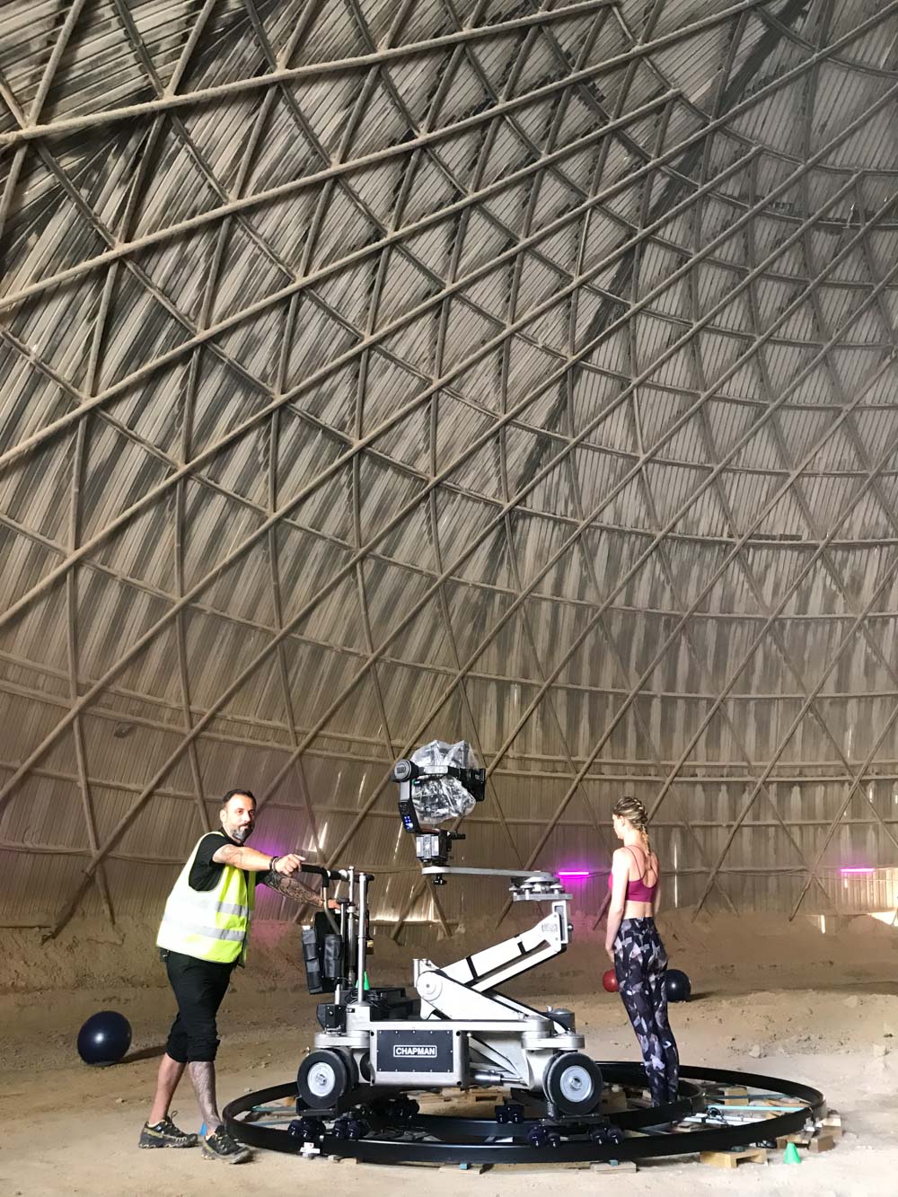 Glassy Films grip pushing a camera dolly on a circular track inside a wooden dome