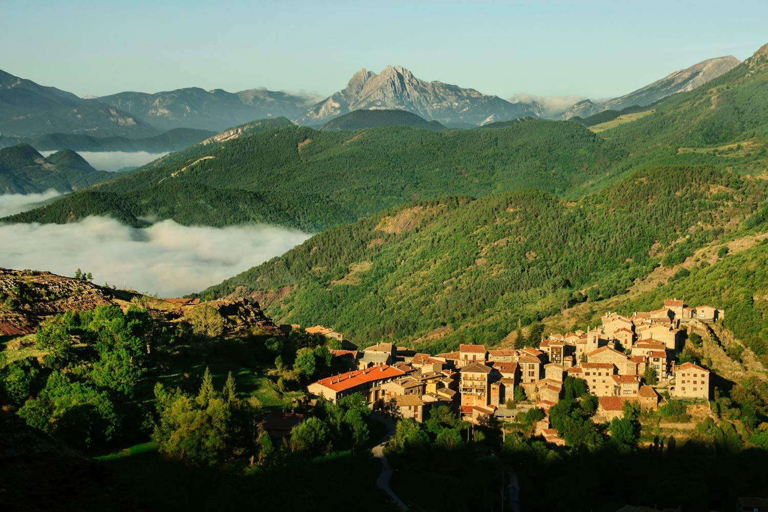 Stone village on a green mountainside in the Catalan Pyrenees at sunrise