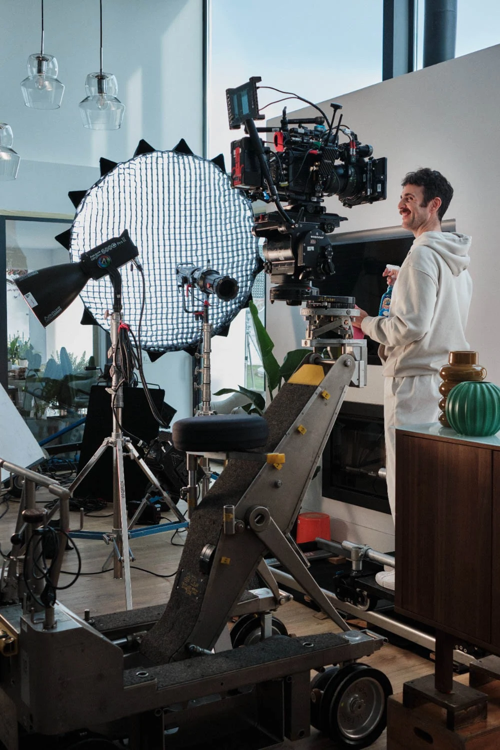 Glassy Films crew member smiling beside a camera crane on a home interior set